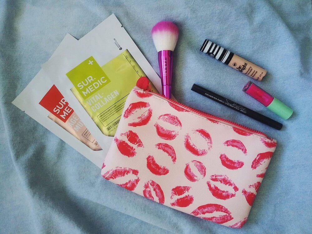 Blue jean background; pink lipstick lip pattern bag; contents of bag (listed below) beside and atop bag