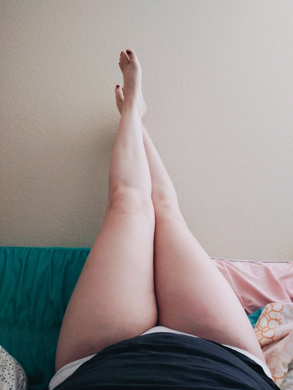 Pants-free legs up against the wall on my bed