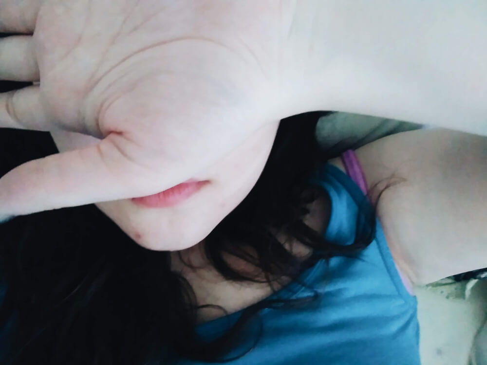 Selfie taken while laying down; hand facing palm-up over face