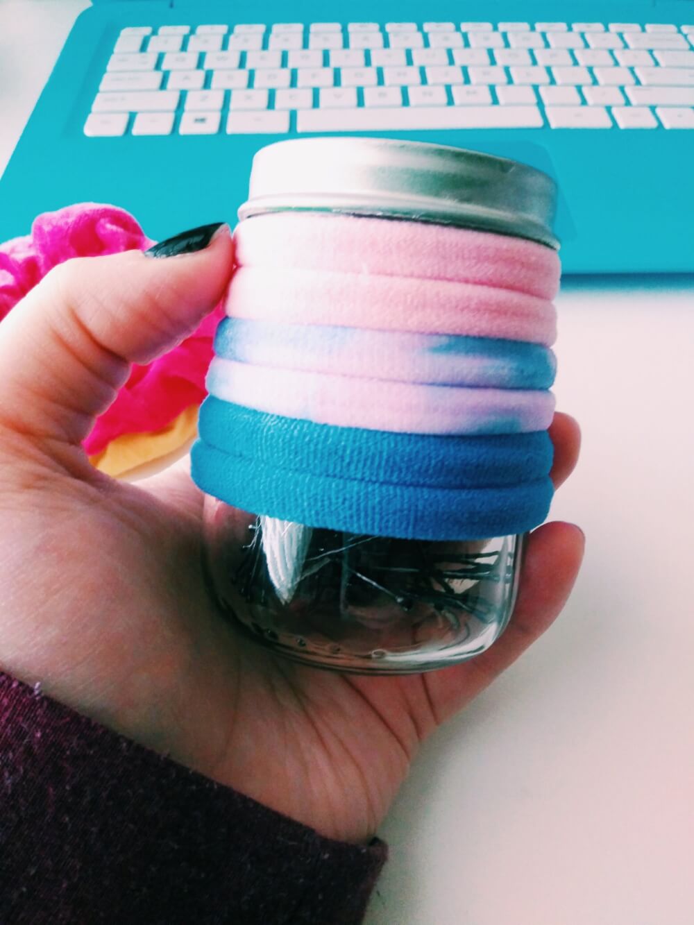 Baby food jar holding bobby pins; spray-painted silver lid; hair elastics around outside of jar