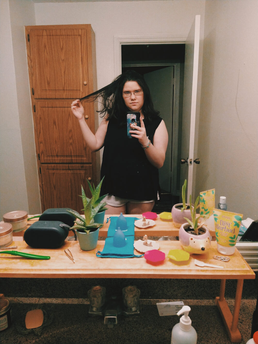 Standing in front of bathroom mirror in boyshorts, holding piece of hair out